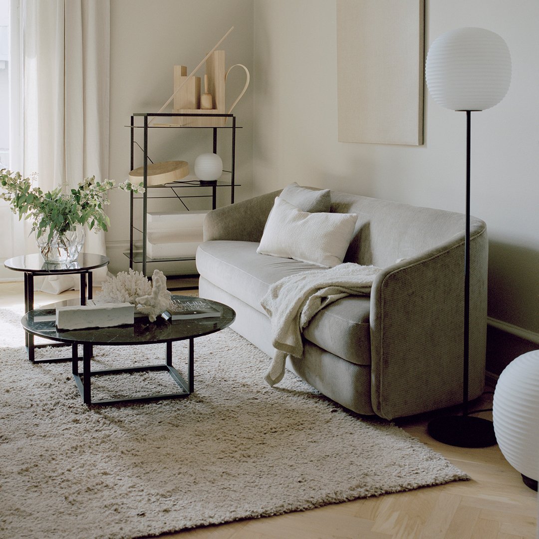 Textured beige couch with white pillows, black coffee table, and soft cream rug in a modern living room setting.