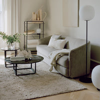 Textured beige couch with white pillows, black coffee table, and soft cream rug in a modern living room setting.