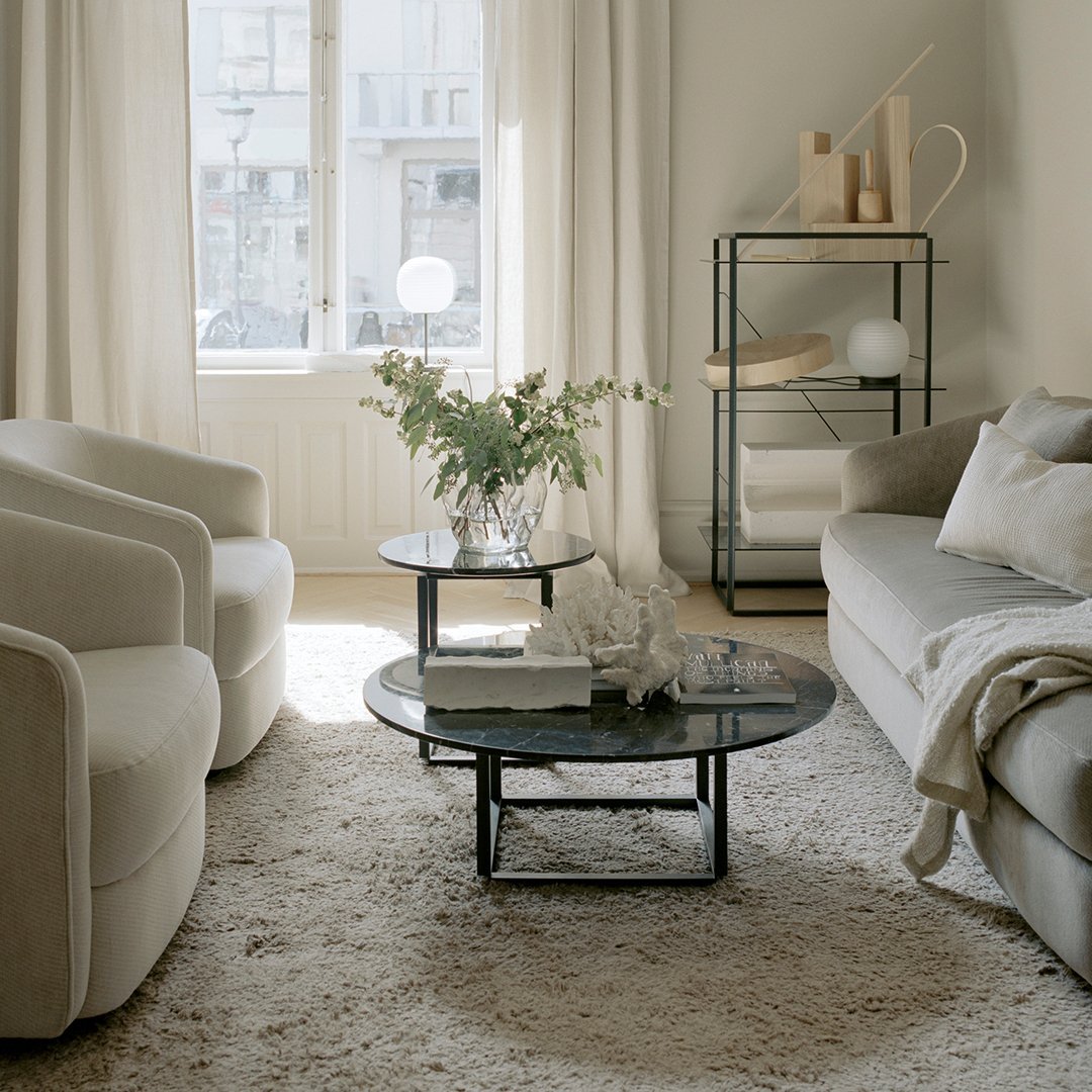 Modern living room featuring neutral tones, soft textures, and minimalist black accents with a cozy beige rug.