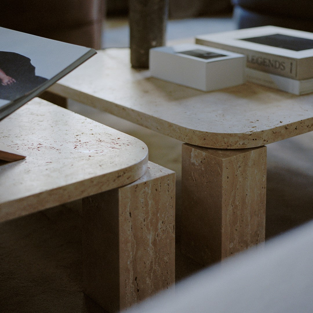Beige stone coffee tables with smooth edges and subtle patterns, complemented by a minimalist design.