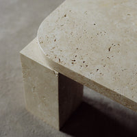 Light beige stone table with natural textures and subtle patterns, featuring rounded edges and a minimalist design.