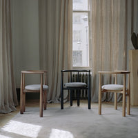 Three chairs in a room with large windows and curtains