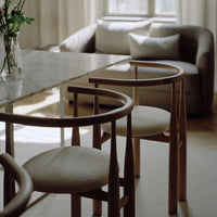 Dining area with marble table and wooden chairs in a softly lit room.