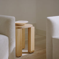 Natural wooden side table with a light beige plate on top, set against soft, neutral background tones.