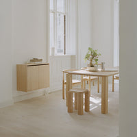 Light wood furniture in a minimalist, neutral-toned room with white walls and soft natural lighting.