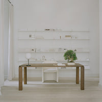 Minimalist white space with a natural wood desk, soft green plant, and subtle beige accents throughout the decor.