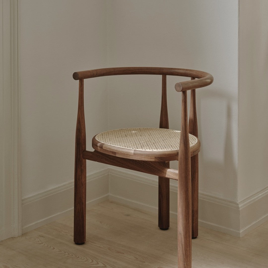 Natural wood chair with a rich brown finish and a light woven cane seat, set against a neutral backdrop.