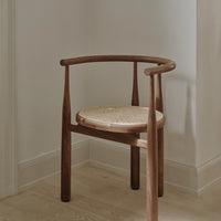 Natural wood chair with a rich brown finish and a light woven cane seat, set against a neutral backdrop.