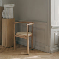 Natural wooden chair with light beige woven seat, featuring smooth curved lines and minimalist design.