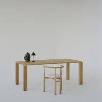 Wooden table and chair in natural tones with minimalistic black and green accents on a light background.