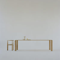 Minimalist light wood table and chair on a soft white background, featuring smooth, clean lines and neutral tones.