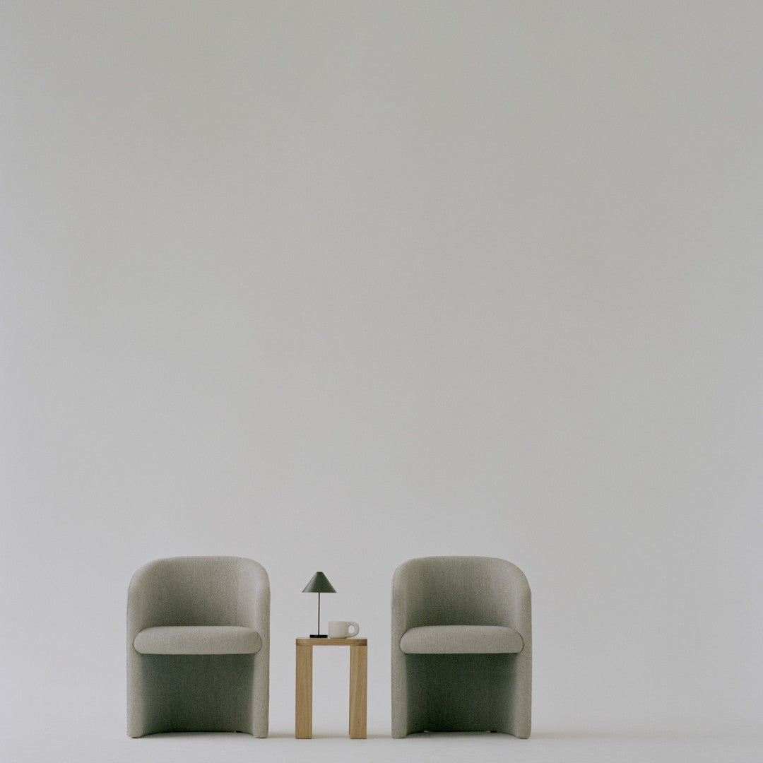 Elegant gray armchairs with a minimalist design, paired with a light wooden table and neutral decor accents.