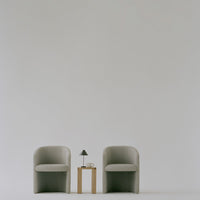 Elegant gray armchairs with a minimalist design, paired with a light wooden table and neutral decor accents.