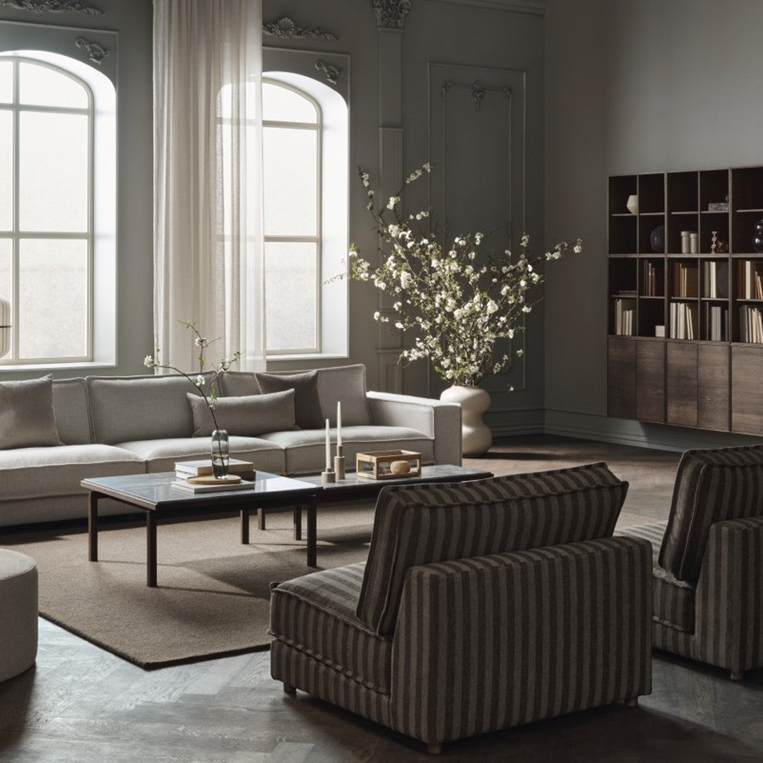 Modern living room with beige, gray tones featuring striped chairs and a neutral rug, accented by a floral arrangement.