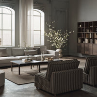 Modern living room with beige, gray tones featuring striped chairs and a neutral rug, accented by a floral arrangement.