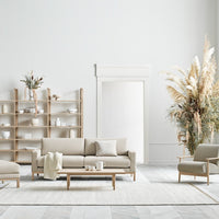 Beige and neutral seating with light wood accents, set against a soft gray and white patterned rug.