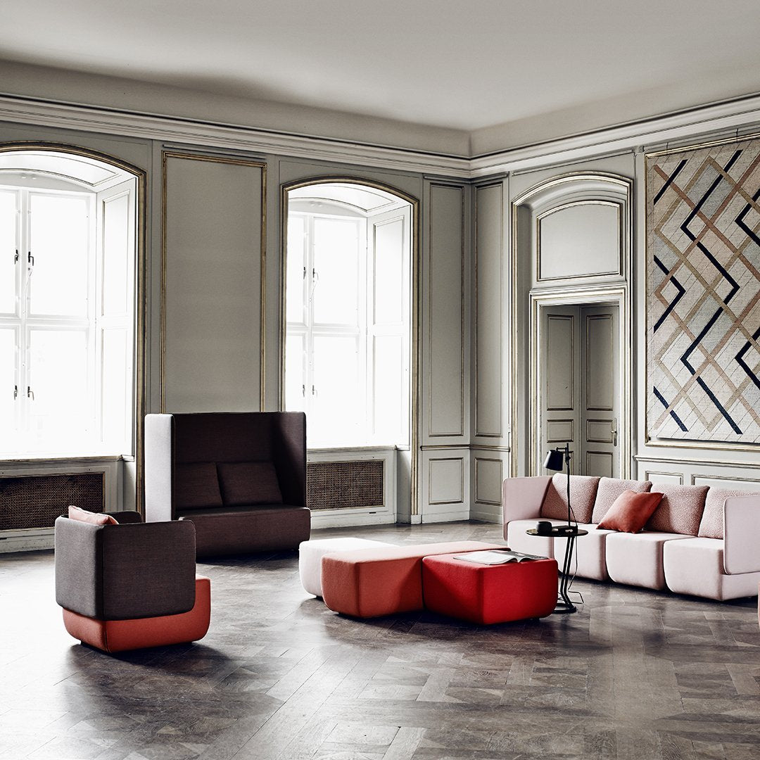 Contemporary seating in soft pinks, deep browns, and vibrant reds, set against elegant patterned walls.