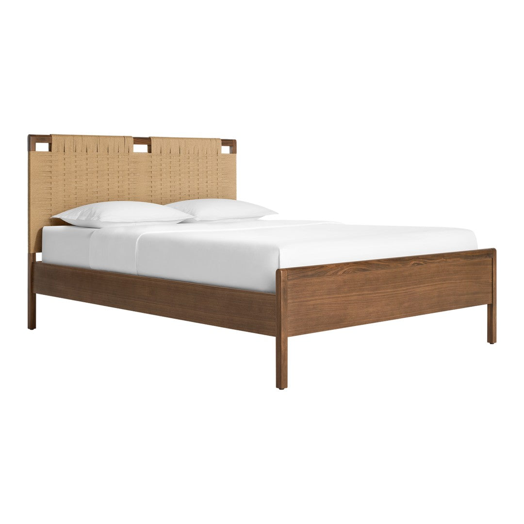 Natural wood tones with a woven tan fabric headboard and white bedding create a cozy, modern aesthetic.