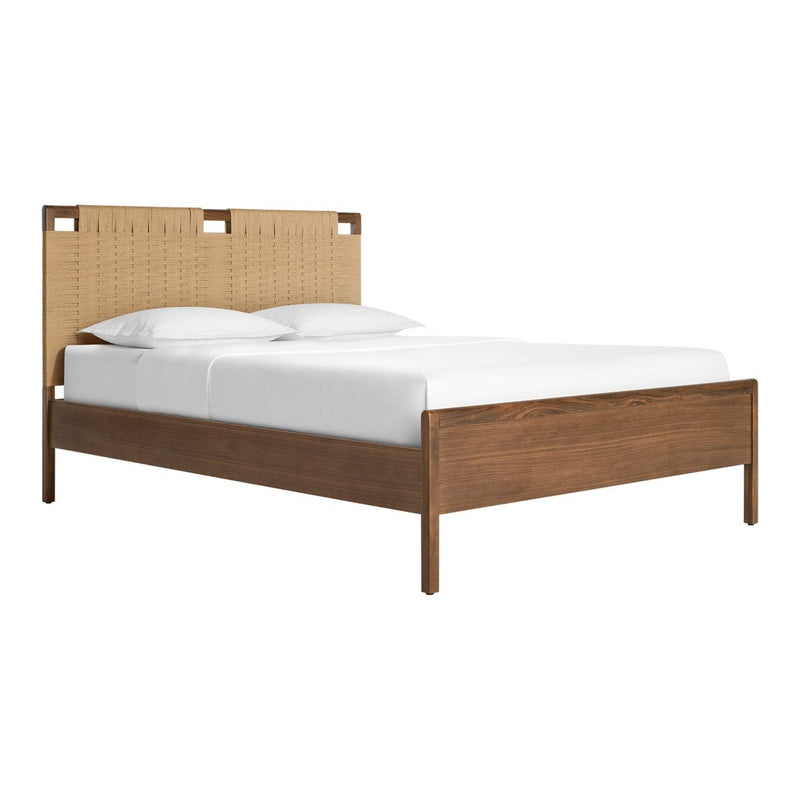 Natural wood tones with a woven tan fabric headboard and white bedding create a cozy, modern aesthetic.