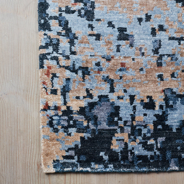 Abstract pattern rug featuring shades of blue, gray, and warm tan tones, blending seamlessly for a modern aesthetic.