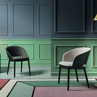 Modern chairs in soft gray and beige against green and blue walls, with a geometric multi-colored rug pattern.