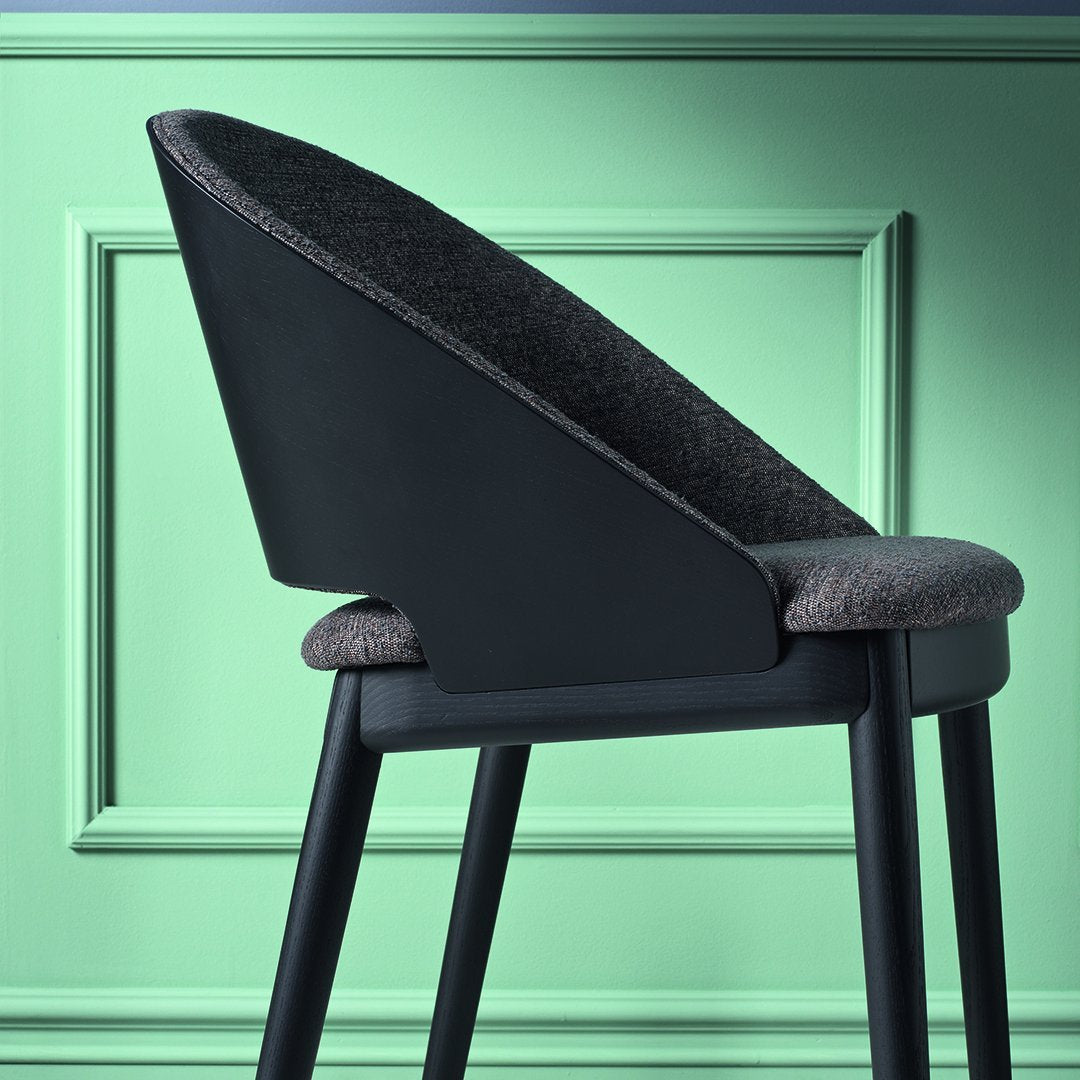 Sleek black chair with a textured charcoal seat against a mint green backdrop, featuring a modern silhouette.