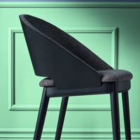 Sleek black chair with a textured charcoal seat against a mint green backdrop, featuring a modern silhouette.