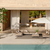 "Neutral-toned outdoor lounge with beige cushions and a white umbrella over a serene, turquoise poolside setting."
