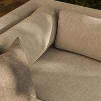 Beige textured sofa with soft cushions, featuring a subtle pattern on a complementary throw pillow. Perfect for modern decor.