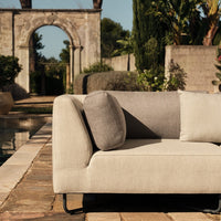 Beige and gray sectional sofa with a modern design and soft textures, featuring a round cushion and sleek lines.