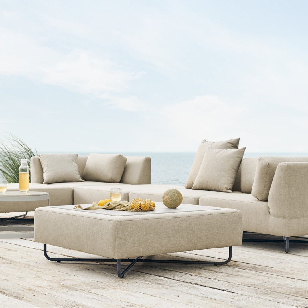 Beige outdoor sectional sofa with plush cushions, modern design, and minimalistic style, perfect for coastal settings.