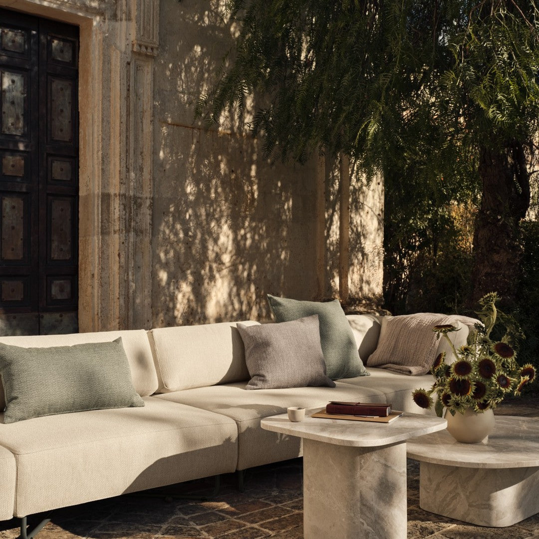 Neutral-toned sectional sofa with soft green and gray accents, surrounded by natural textures and subtle patterns.