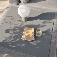 Gray tabletop with soft shadows, a white lamp, a beige book, and a small glass with a lime slice. Minimalistic design.