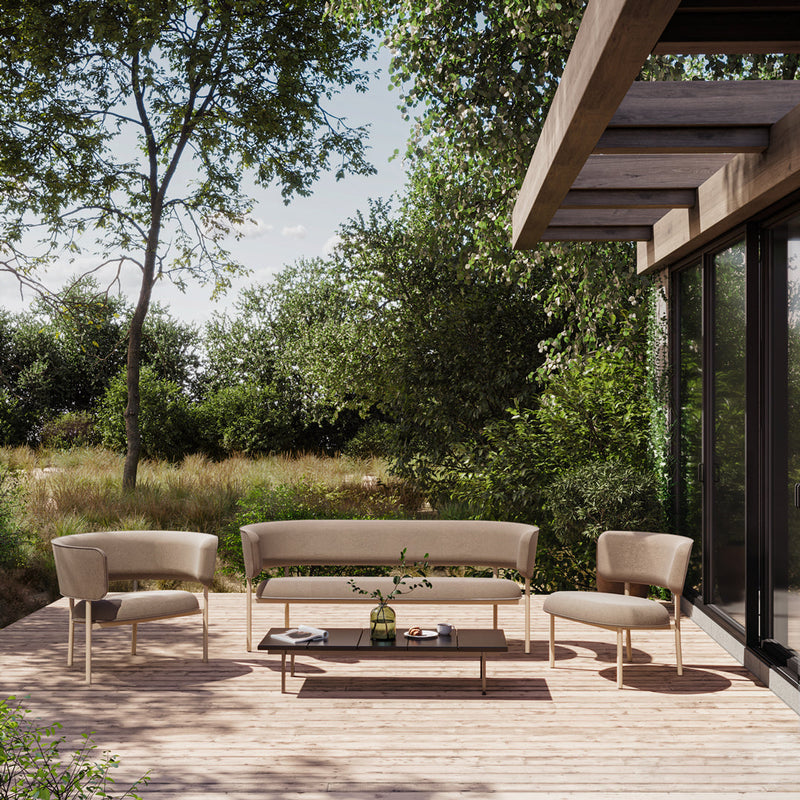 Beige outdoor seating set with smooth textures, surrounded by lush greenery and natural wood decking.