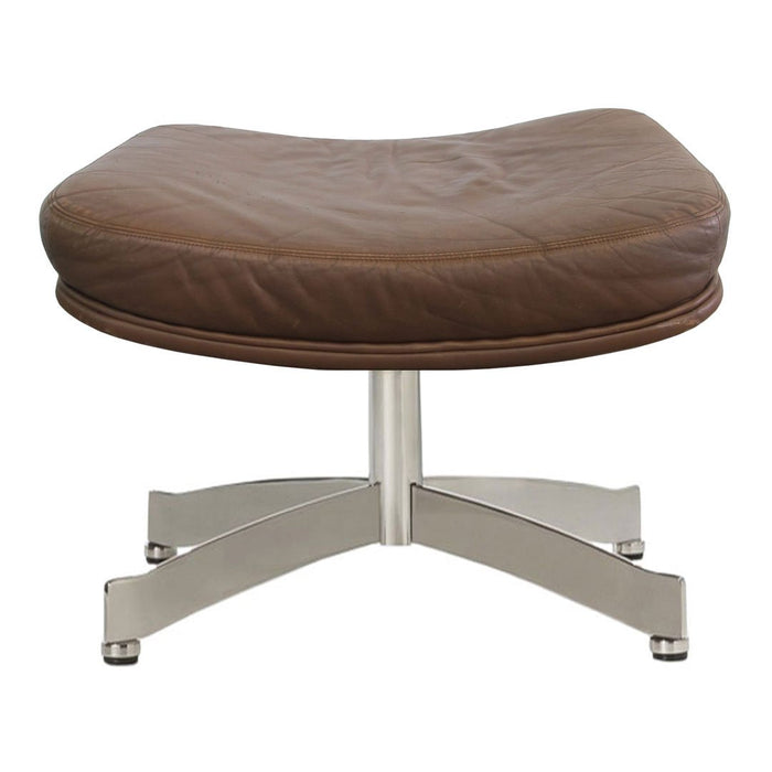 Brown leather ottoman with a smooth, curved surface and sleek silver metal base.