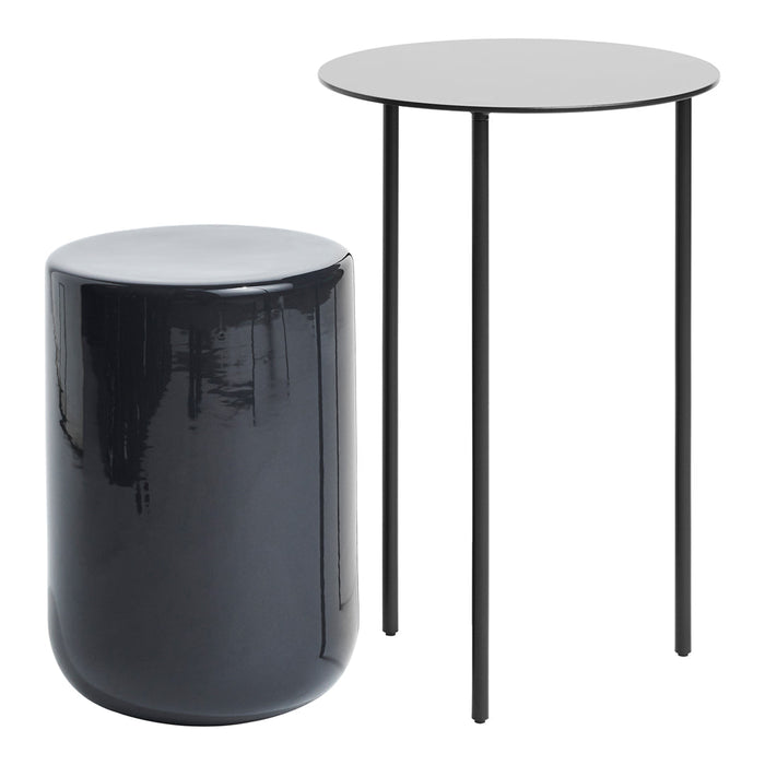 Black glossy cylindrical stool beside a sleek round black table with slender legs. Modern design and minimalist style.