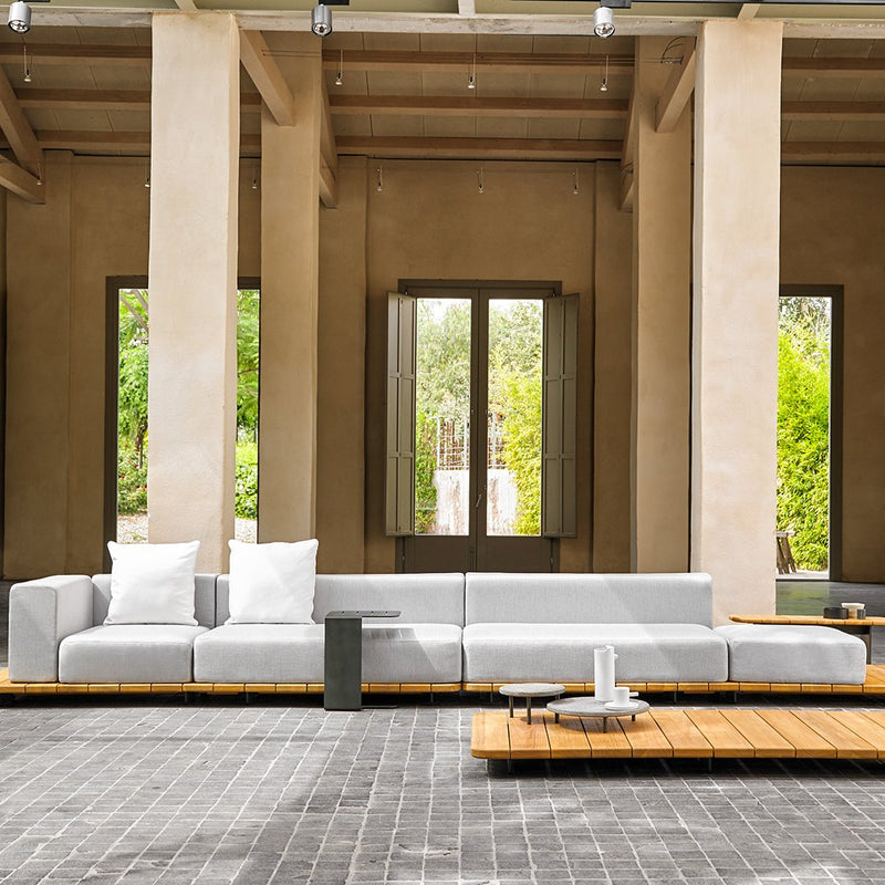 Modern gray sectional sofa with white cushions, set against a neutral beige backdrop, featuring natural wood accents.