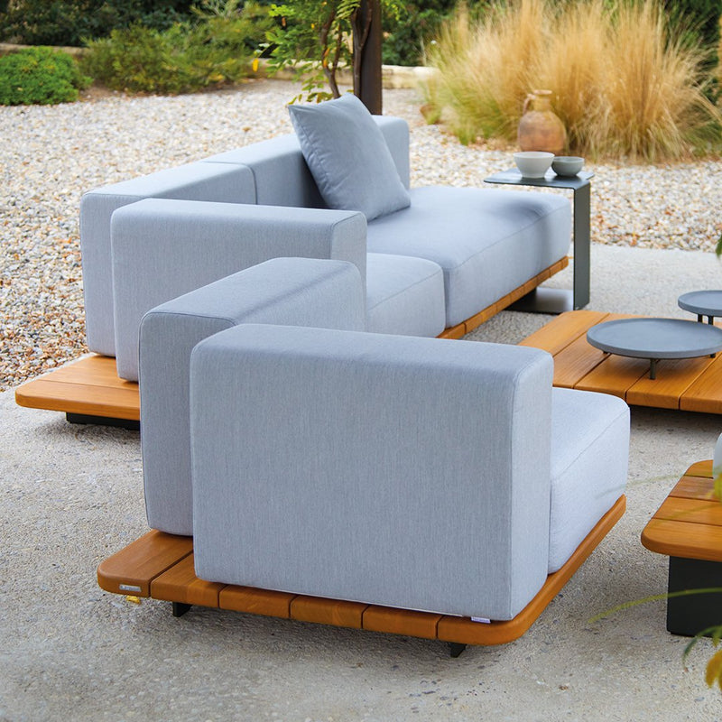 Light gray outdoor sofa with minimalist design, paired with wooden platform coffee tables. Elegant and modern aesthetics.