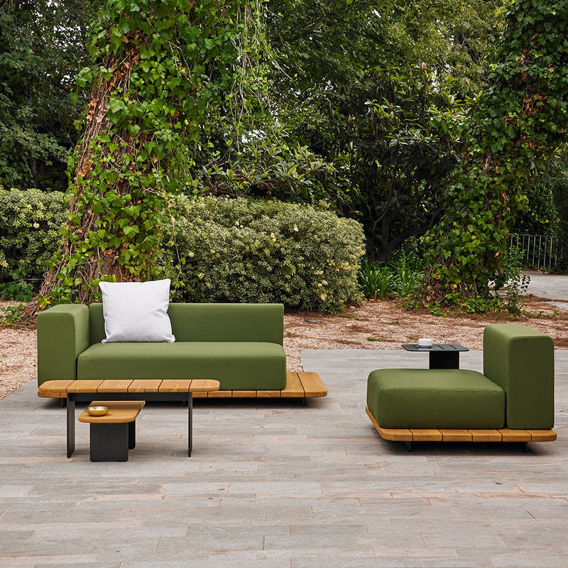Green outdoor sofa set with minimalist design and wooden accents, featuring a white cushion and earthy tones.