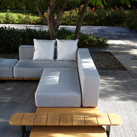 Modern outdoor sectional sofa in soft gray fabric with white cushions and natural wood accents. Perfect for stylish patios.