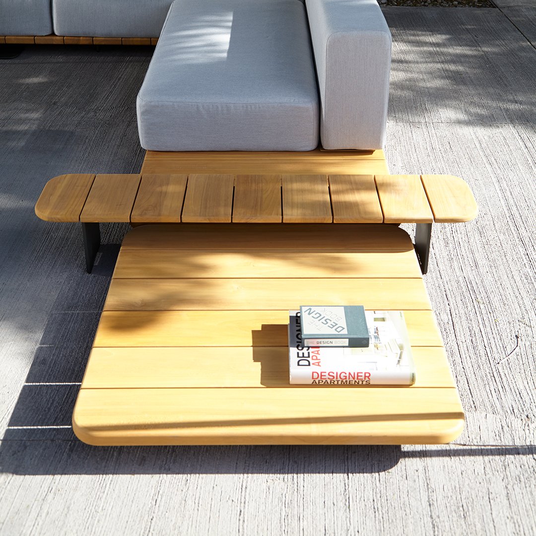 Sunlit wooden coffee table with a sleek yellow finish, complemented by a light gray sofa and minimalist design.