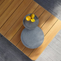 Gray stone bowls with smooth surfaces, featuring bright yellow lemons, set on a warm wooden table.