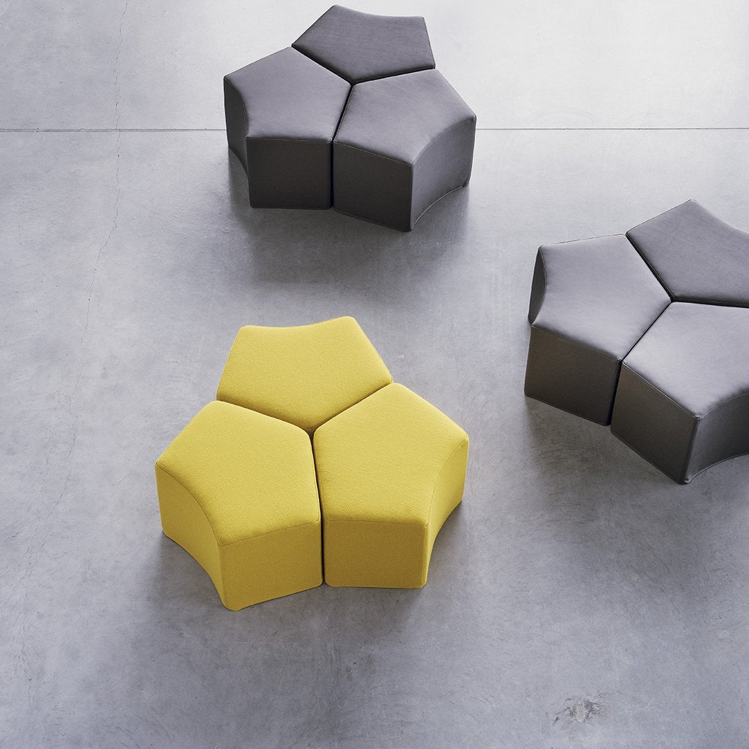Hexagonal seating with a vibrant yellow piece surrounded by gray, featuring clean lines and modern design.