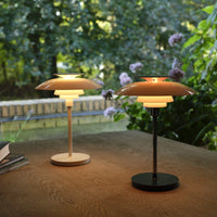 Two stylish lamps featuring warm beige and sleek black colors, with unique layered designs on wooden surface.