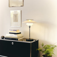Modern table lamp with a soft white shade, black base, and warm gold accents, enhancing any décor with elegance.