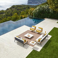 "Modern outdoor seating set with gray cushions, yellow accents, and a stylish brown tabletop, surrounded by lush greenery."