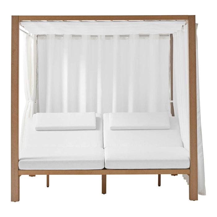 "White canopied daybed with natural wood frame and soft white cushions, featuring elegant draped fabric."