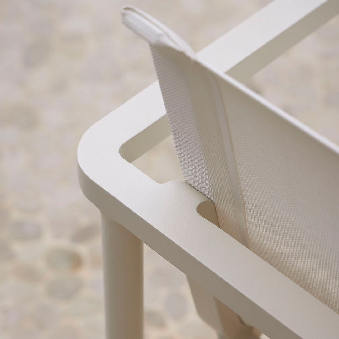 White minimalist chair showcasing smooth lines and a sleek design against a textured neutral background.