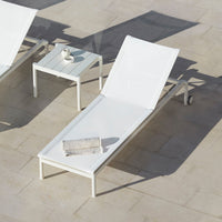 White modern lounge chair with sleek lines and minimalistic design, set on a light-colored tiled surface.