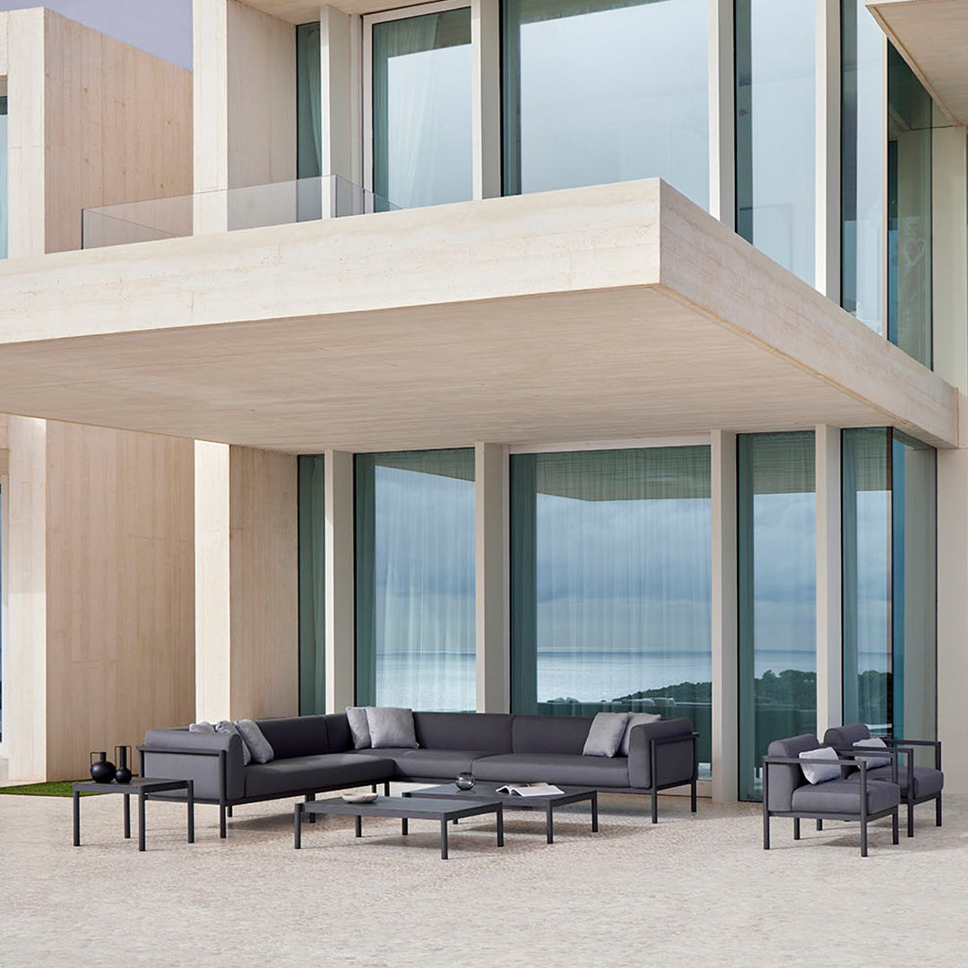 Modern outdoor sofa set in sleek black, featuring a minimalist design with gray and white accent cushions.